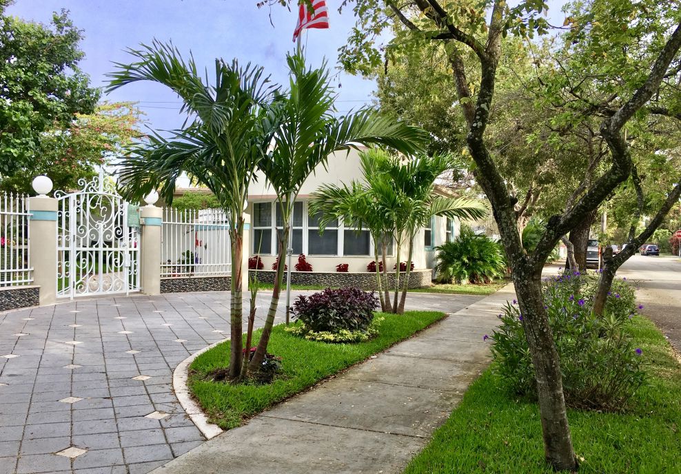 Gated walkway with palms leading to the Azalea Gardens assisted living residence in Hollywood, Florida
